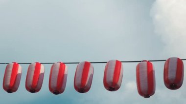 Kırmızı-beyaz Japon lambaları Chochin kağıt mavi bulutlu gökyüzü arka plan üzerinde asılı.