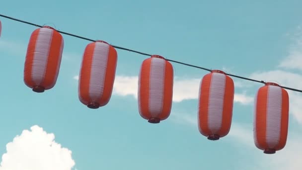 Lanternes japonaises papier rouge-blanc Chochin accroché sur fond bleu ciel nuageux — Video