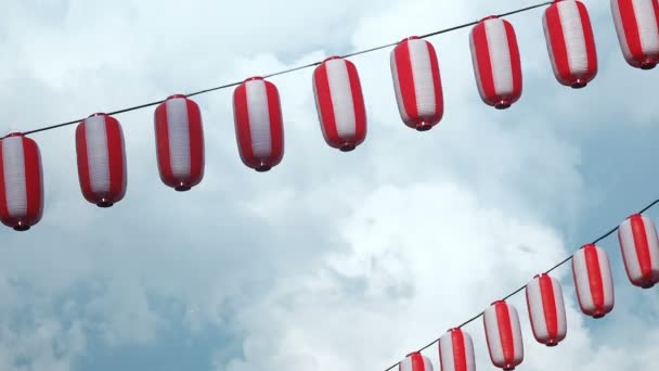 Papel rojo-blanco linternas japonesas Chochin colgando sobre fondo azul cielo nublado — Vídeos de Stock