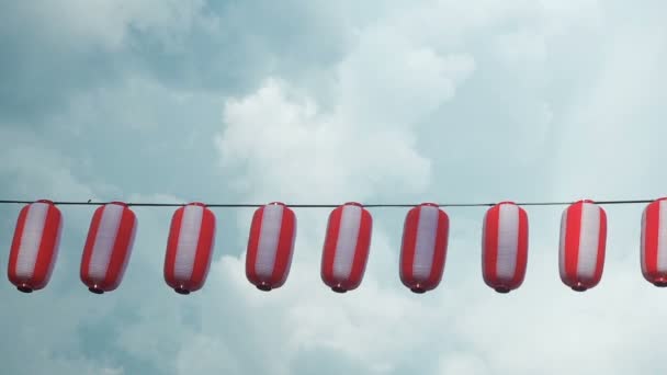 Papierowe latarnie japońskie czerwono białe Chochin wiszące na tle niebieskiego nieba deszczu — Wideo stockowe