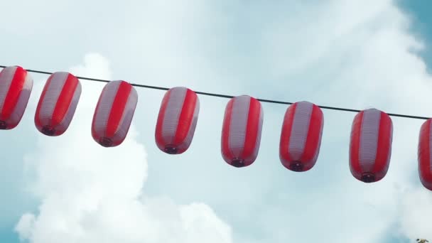 Papier rood-witte Japanse lantaarns Chochin opknoping op blauwe bewolkte hemelachtergrond — Stockvideo