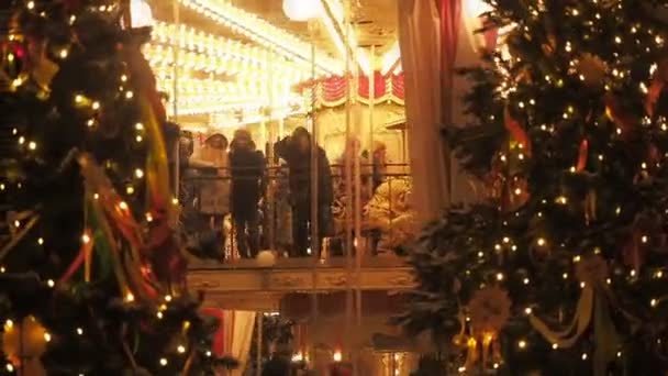 MOSCÚ - 25 DE DICIEMBRE DE 2017: La gente en el carrusel cerca de la Plaza Roja decoró los árboles de Navidad y organizó la Navidad y el Año Nuevo. Feria de Navidad festiva. Rotonda luminosa gira con adultos y — Vídeos de Stock