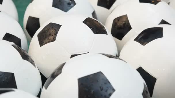 Viele schwarze und weiße Fußballbälle Hintergrund. Fußballbälle schwimmen in reinem Wasser aus nächster Nähe — Stockvideo