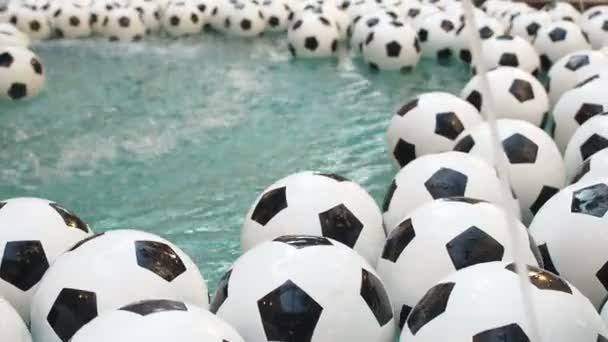 Muitas bolas de futebol preto e branco fundo. Bolas de futebol Natação em uma água pura — Vídeo de Stock