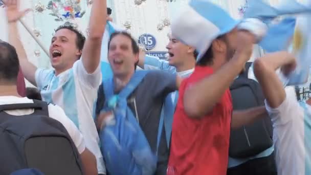 MOSCOW, RUSSIA, JUNE 20, 2018: Soccer World Cup Argentine football fans in caps with symbols of the national team with flags at the on Nikolskaya Street jumping singing songs, a crowd with mobile — Stock Video