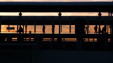 Metro tren istasyonuna, insanlar platformda günbatımı sırasında yürüyüş tren arabaları ayrılan girme siluet. Tren Istasyonu sahnesinde: insan içinde eve dönüş