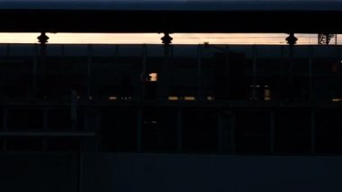 Metro tren istasyonunda, insanlar platformda günbatımı sırasında yürüyüş tren arabaları ayrılan gelen silüeti. Tren Istasyonu sahnesinde: insanlar akşamları eve dönüş