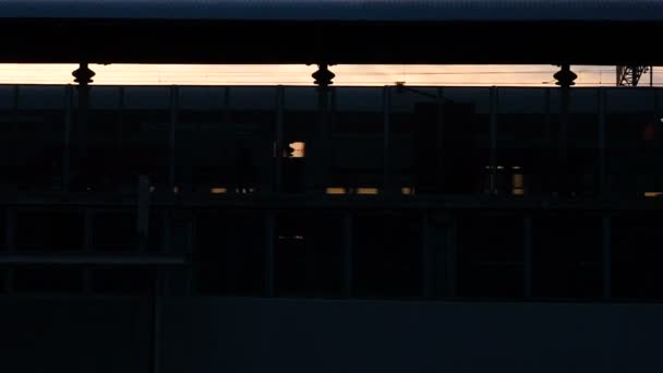 Силуэт поезда метро, прибывающего на станцию, люди, покидающие железнодорожные вагоны, идущие по платформе во время захода солнца. Scene on the railway station: People return home in the evening — стоковое видео