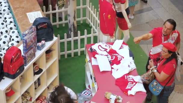 Moskau, russland - 5. August 2018: Touristen kaufen offizielle Fußballuniformen als Souvenir am Point of Sale eines Sportgeschäfts in Kaugummi, Moskau. ein Mann zeigt seiner Frau eine Sache auf einer Schaufensterpuppe, die — Stockvideo