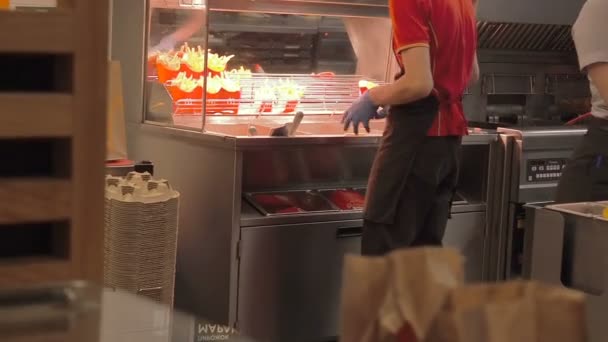 Москва, Россия - 16 сентября 2018 года: Готовим картофель во фритюре в McDonalds. Фастфуд картофель фри приготовления в кипящем масле. Мужчина и женщина работают в сети ресторанов быстрого питания на кухне — стоковое видео