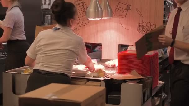 Moskva, Ryssland - 16 September 2018: Förpackningar restaurang arbetare hamburgare i lådor. Personalen förbereder hamburgare och packar det i ett paket. Fungerar i kök snabbmat restaurang kedjan. McDonalds — Stockvideo