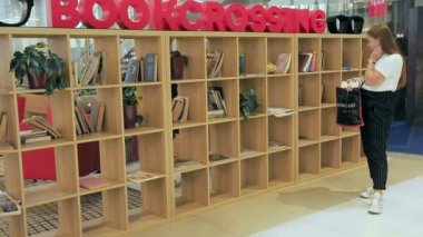 Moscow, Rusya Federasyonu - 16 Eylül 2018: Kız Bookcrossing raf üzerine bir kitap seçer. Ahşap raf kitaplar bitiren insanlar arasındaki değişimi için kitap okumak