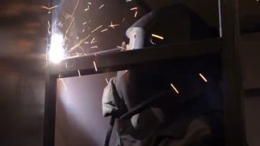Kaynakçı işçi atlama kaynak gerçekleştirir. İşçi kaynakçı ark kaynağı süreci Metal yapılar gerçekleştirir. Kaynak Makinası kıvılcımlar uçuşuyordu. Kaynakçı Metal profilleri ikinci kat kapalı kaynak.