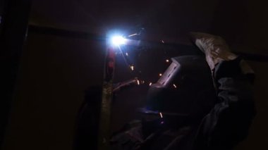 Kaynakçı işçi atlama kaynak gerçekleştirir. İşçi kaynakçı ark kaynağı süreci Metal yapılar gerçekleştirir. Kaynak Makinası kıvılcımlar uçuşuyordu. Kaynakçı Metal profilleri ikinci kat kapalı kaynak.