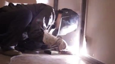 Kaynakçı işçi atlama kaynak gerçekleştirir. İşçi kaynakçı ark kaynağı süreci Metal yapılar gerçekleştirir. Kaynak Makinası kıvılcımlar uçuşuyordu. Kaynakçı Metal profilleri ikinci kat kapalı kaynak.