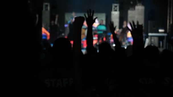 Gelukkig publiek Raisies twee handen in Turn Rock groep concertzaal Silhouettes dansende mensen applaudisseren verhogen handen omhoog menigte juicht ritme muziek muzikanten voeren fase — Stockvideo