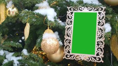 Kıvırcık kar ile serpilir köknar ağacı asılı resim çerçevesi oyulmuş. Beyaz çerçeve içine eklenen yeşil Chroma Key. Boş fotoğraf çerçevesi Noel ve yeni yıl arka plan, boş Mockuptemplate.