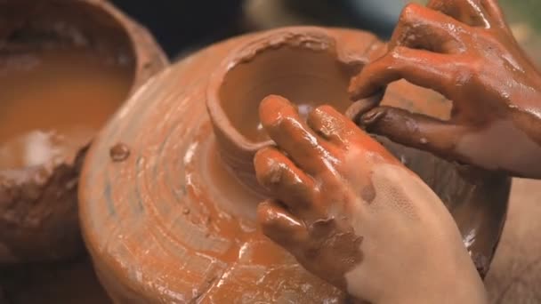 Roue de potiers rotatifs et de la vaisselle d'argile sur elle prise d'en haut. Un enfant sculpte ses mains avec une tasse d'argile sur une roue de potiers. Les mains dans l'argile. Céramiste masculin poterie crée un produit en argile fait main — Video