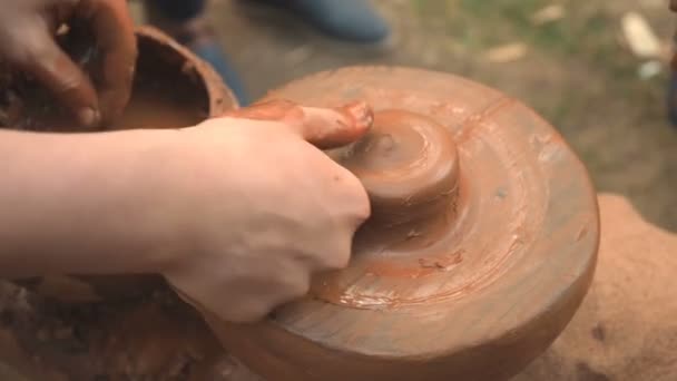 Rotating potters wheel and clay ware on it taken from above. A sculpts his hands with a clay cup on a potters wheel. Hands in clay. Pottery male ceramist creates a hand made clay product. Process of — Stock Video