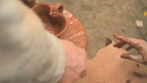 Roue de potiers rotatifs et de la vaisselle d'argile sur elle d'en haut. Un enfant sculpte ses mains avec une tasse d'argile en forme de cœur sur une roue de potiers. Les mains dans l'argile. Céramiste de poterie a créé un produit en argile fait main — Video
