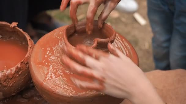 Обертові гончарні колеса і глиняний посуд на ньому взяті зверху. Дитина скульптури його руки з глиняною чашкою на гончарному колесі. Руки в глині. Керамічний чоловічий кераміст створює ручний глиняний продукт — стокове відео