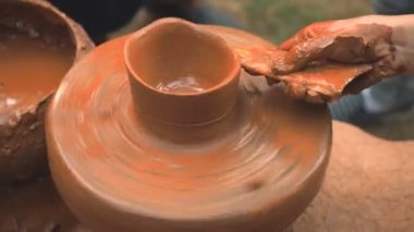 Dönen tekerlek potters ve bir desen kil eşya üzerinde yapar. Bir çocuk bir kil Kupası potters tekerlek üzerinde elleriyle sculpts. Kil elinde. Çanak çömlek erkek ustası bir el yapımı kil ürün oluşturur. İşlem