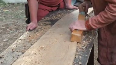 Uçakla bir ahşap çalışma Ortaçağ pamuklu giysiler içinde bir marangoz. Adam el ile bir ahşap tahta bir uçakla Hews