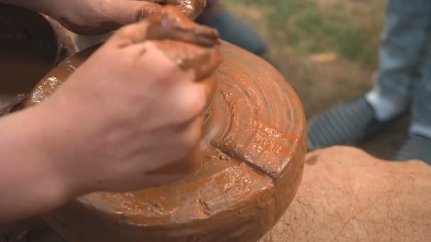 Обертові гончарні колеса і глиняний посуд на ньому взяті зверху. Скульптури руками з глиняною чашкою на гончарному колесі. Руки в глині. Керамічний чоловічий кераміст створює ручний глиняний продукт. Процес створення — стокове відео