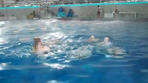 Синхронное плавание. Стройные ноги девушки спортсменки торчат из воды в открытом бассейне зимой. Молодые девушки учатся плавать в бассейне. Молодых девушек учат плавать в бассейне — стоковое видео