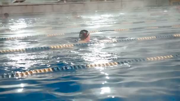 Actieve mensen zwemmen in een sport-zwembad buiten in de winter. Zwemmen in de openlucht bekken in de winter. Mannen en vrouwen zwemmen in schoolslag stijl — Stockvideo