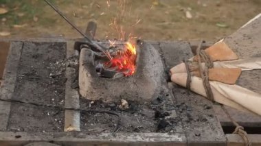 Eski moda körük forge çalışan demirci. Demirci kütük bir kil Fırında sıcak kömürlerin üzerinde tutar. demir metal kılıç imalatı yürüyen forge Isıtma demirci
