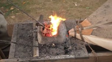 Eski moda körük forge çalışan demirci. Demirci kütük bir kil Fırında sıcak kömürlerin üzerinde tutar. demir metal kılıç imalatı yürüyen forge Isıtma demirci