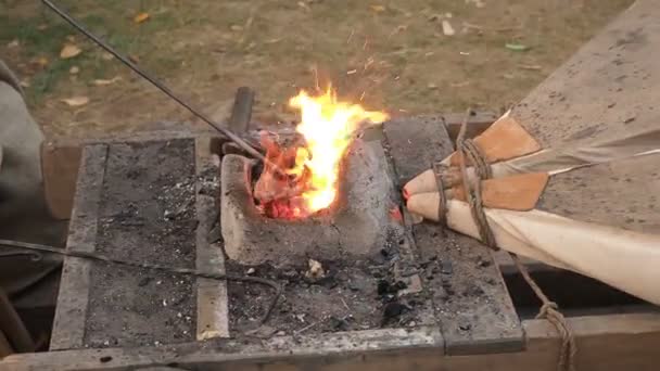 Blacksmiths working old fashioned bellows at the forge. The blacksmith holds the billet over hot coals in a clay oven. blacksmith heating iron metal sword manufacturing marching forge — Stock Video