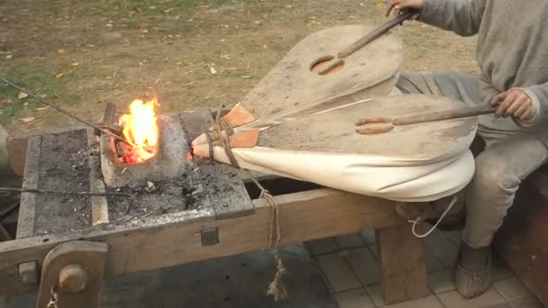 오래 된 구식된 풀 무 위조에서 작동 하는 대장장이. 대장장이 찰 흙 오븐에서 뜨거운 불길 위에 지위를 보유 하고있다. 난방 철 금속 칼 행진 포지를 제조 하는 대장장이 — 비디오
