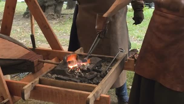 Kovář drží sochorové přes žhavé uhlí v hliněné peci. kováři topení Železný kovový meč výrobní pochodující forge — Stock video