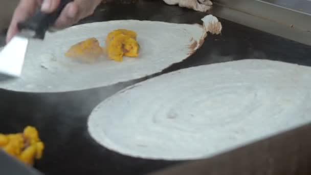Crepes de desayuno indios hechos de lentejas y arroz Dosa, de cerca. Cocinar comida rápida en la calle india al aire libre. El cocinero hornea panqueques en un horno precalentado y lo llena con arroz y relleno de especias . — Vídeos de Stock