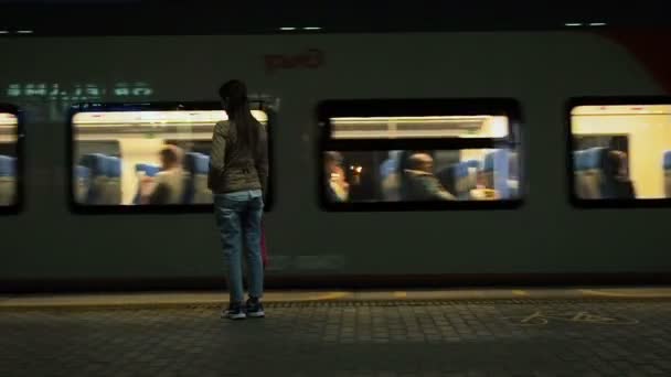 Mosca, Russia - 20 agosto 2018: La donna aspetta il treno alla stazione della metropolitana la sera. La ragazza si avvicina alle carrozze del treno in avvicinamento. Partenza treno della Centrale di Mosca — Video Stock