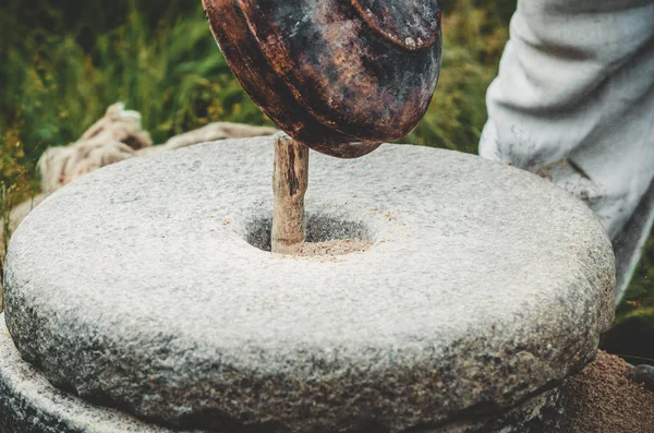 고 대 quern 돌 손을 밀 곡물. 밀의 구멍에 곡물을 따르는 사람. 오래 된 연 삭 돌 손에 의해 설정. — 스톡 사진