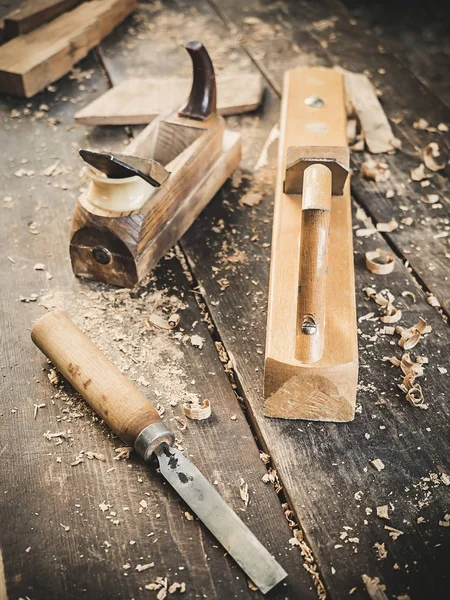 Herramienta de mano de carpintería antigua: plano de madera, cincel y en un taller de carpintería sobre una mesa rústica sucia cubierta con vista lateral de fondo de serrín — Foto de Stock