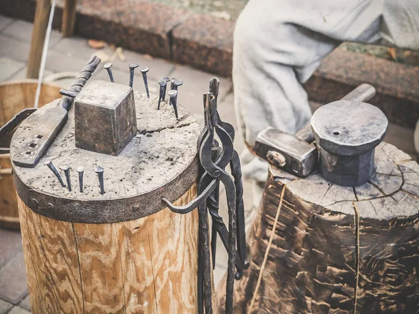 Herramientas metalúrgicas del herrero. El martillo y el yunque y otras herramientas al aire libre verde hierba fondo . — Foto de Stock