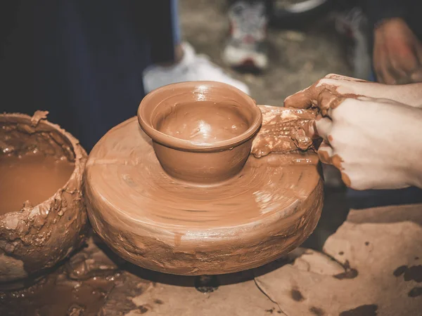 Rueda giratoria de alfareros y vajilla de arcilla en ella tomada desde arriba. Un niño esculpe sus manos con una taza de barro sobre una rueda de alfarero. Manos en arcilla. Cerámica cerámica masculina crea un producto de arcilla hecha a mano — Foto de Stock