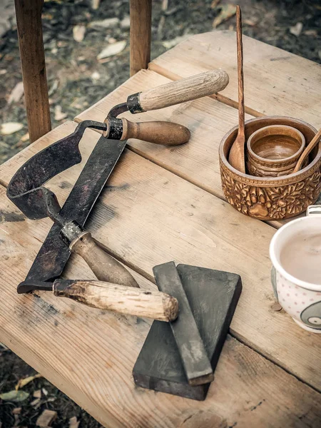Старый деревянный ручной нож, лосьон, рисование ножа, бритье ножа деревянный в столярной мастерской на грязном деревенском столе со старыми глиняными untensils вид сбоку — стоковое фото