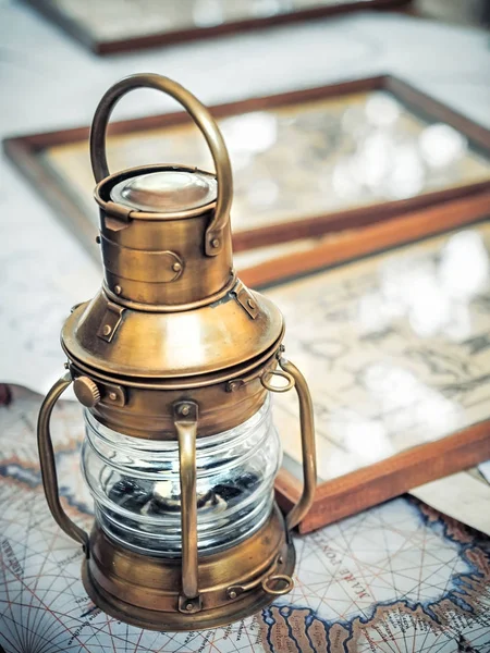 老黄铜船灯笼站立在海地图附近图片与海结的图 免版税图库图片