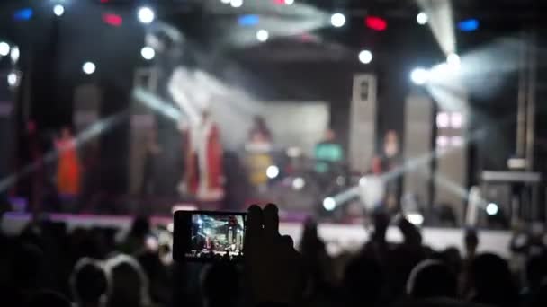 Handen håller rekord Video kamera Smartphone Live konsert prestanda tar foto musik bandet silhuetter dansande människor som applåderar att höja händerna upp publiken applåderar rytm musik musiker utföra scenen — Stockvideo