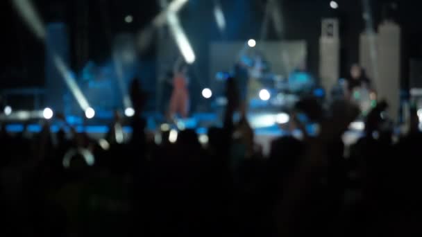 Blaue Zeitlupe Video Hintergrund Publikum wedelt mit den Armen in verschiedene Richtungen Rosetten Hände Rockgruppe Konzerthalle Silhouetten tanzende Menschen Hände nach oben Menge Rhythmus Musik Musiker führen Bühne — Stockvideo