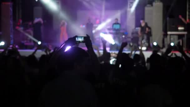 Slow Motion Video achtergrond gelukkig publiek Raisies handen Toon vorm hart concertzaal silhouetten dansen mensen applaudisseren verhogen handen omhoog menigte juicht ritme muziek muzikanten voeren fase — Stockvideo