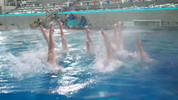 Natación sincronizada. Chicas piernas delgadas atletas sobresalen del agua en la piscina abierta en invierno. Las chicas jóvenes aprenden a nadar en la piscina. Las chicas jóvenes están entrenadas para nadar en la piscina — Vídeo de stock