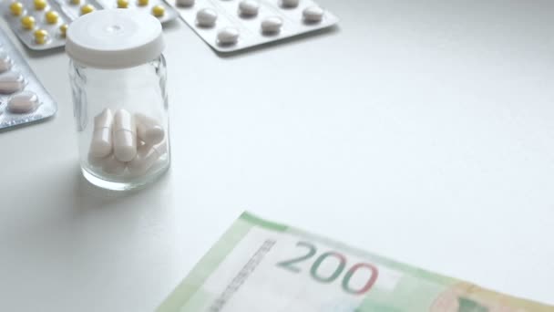Για να μετρήσω τα λεφτά. Πλήρωσε τα φάρμακα για το φάρμακο. Οι άνθρωποι αγοράζουν ναρκωτικά. Χάπια φάρμακα ή κάψουλες με χρήματα σε λευκό φόντο. Ένα άτομο πληρώνει με Ρωσικά ρούβλια για φάρμακα σε ένα φαρμακείο. Φαρμακευτικά — Αρχείο Βίντεο