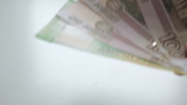 Menselijke hand met een fan van geld. Zetten geld op de tafel. Om geld te tellen. Handen vertellen bankbiljetten op een witte tafel. Mensen hand legt Russische roebels bankbiljetten nominals 200 en 100 op een wit — Stockvideo