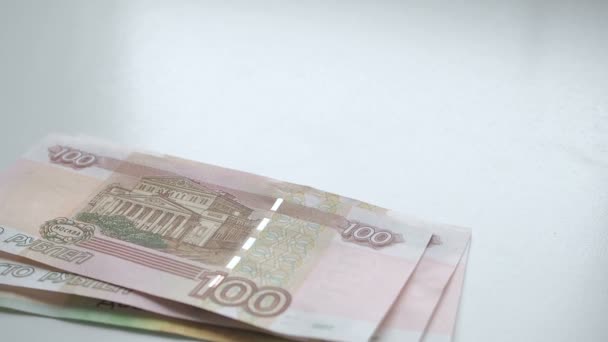 Να μετρήσετε τα χρήματα. Χρήματα που πέφτει σε έναν λευκό πίνακα. Άνθρωποι χέρι ρίχνει Ρωσικά ρούβλια τραπεζογραμμάτια nominals 200 και 100 γρήγορα και κέρματα ονομαστικής 10 σε λευκό φόντο — Αρχείο Βίντεο